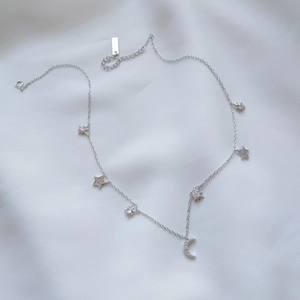 Detailed view of silver star and moon pendant necklace on white silk background