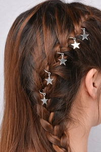 Detail of silver star pendants and hair rings worn on a braided hairstyle for women