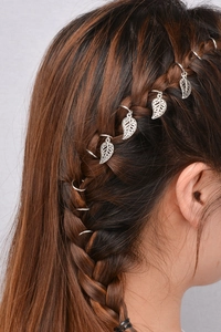 Close-up of silver hair rings and leaf pendants woven into a stylish side braid