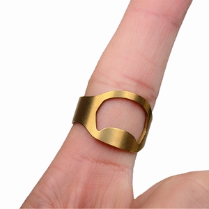 Macro shot of a gold bottle opener ring on a finger highlighting the matte metal texture