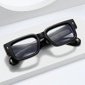 Classic black rectangle thick frame glasses with gold metal rivets on white pedestal