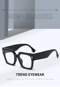 Close-up of black oversized square frame glasses with gold metal accents on front edges