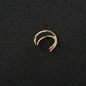 Nahaufnahme eines minimalistischen doppelten Gold-Ohrclips auf Texturmatte