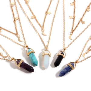 Detail of multi-layered gold necklaces featuring colorful hexagonal crystal pendants and star charms