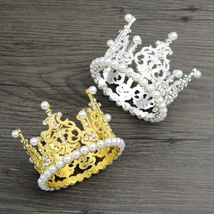 Detailed close-up of gold and silver mini pearl crowns on a dark wood background