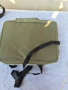 Detail of army green canvas pet travel carrier with adjustable black straps on white soft rug