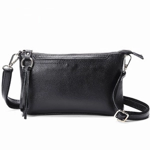Detail of black pebbled leather crossbody bag with silver zipper and texture