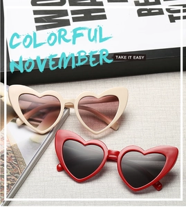 Close-up of heart-shaped sunglasses in cream and red colors with dark tinted lenses