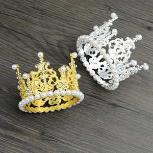 Elegant gold and silver alloy crowns with lustrous pearls on a dark wood background