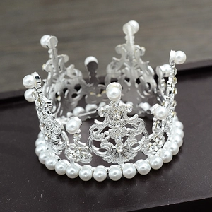 Macro view of silver crown featuring baroque scrolls, clear rhinestones and white pearls