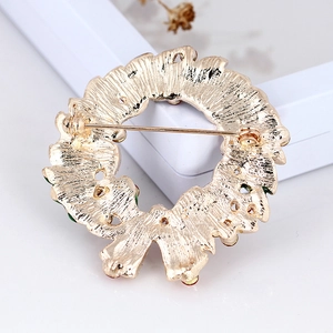 Broche couronne de Noël dorée avec vue sur l'épingle arrière et texture métal
