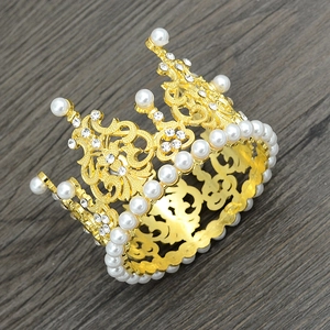 Top view of gold alloy crown with white pearls and rhinestones on a wooden background