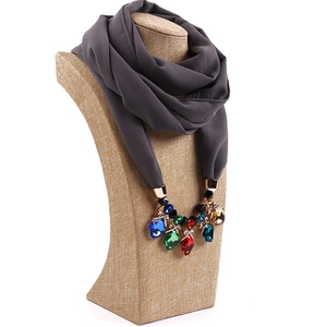 Detail of dark grey chiffon scarf with colorful gemstone pendants and gold metal accents