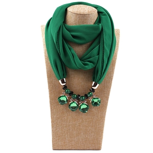 Detail of dark green chiffon scarf necklace with faceted green crystal and gold metal hardware