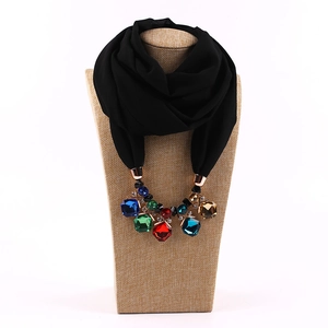 Detail of black chiffon scarf necklace with rose gold clasp and multi-color gemstones