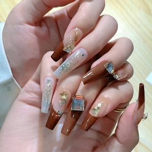 Close-up of long coffin nails featuring brown gradients and luxury crystal decorations
