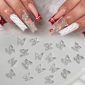 Silver hollow bow butterfly nail charms on festive red manicure and white background