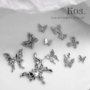Macro view of silver 3D metal butterfly nail charms showing intricate textures and patterns