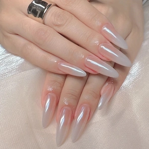 Gros plan d'ongles stiletto avec dégradé aurore blanc nacré sur satin rose doux