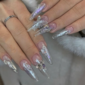 Vista detallada de uñas stiletto con adornos de mariposas 3D y purpurina plateada