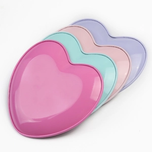 Close-up of heart-shaped stainless steel trays in pastel pink, green, and purple finishes