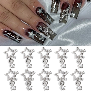 Detailed view of silver hollow star nail charms with rhinestones on silk and hand