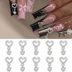 Macro detail of silver heart nail pendants with rhinestones on long coffin nails