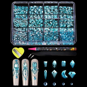 Macro view of 12-grid light blue nail art rhinestones with tweezers and picker pen tools