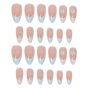 Almond-shaped French press-on nails with nude pink base, blue tips, and white flower patterns