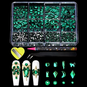 Detail view of emerald green nail art rhinestones kit with wax pen and tweezers on black background