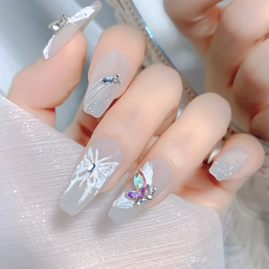Macro shot of long trapezoid press-on nails with 3D butterfly crystals and silver glitter