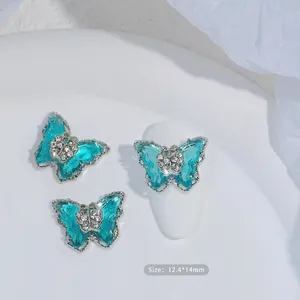 Detalle de dijes para uñas de mariposa de circón verde azulado con bordes de metal plata