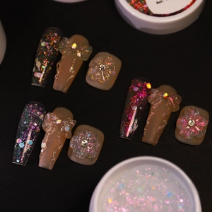 Detail of glitter nail extension gel with 3D bow and floral nail art decorations