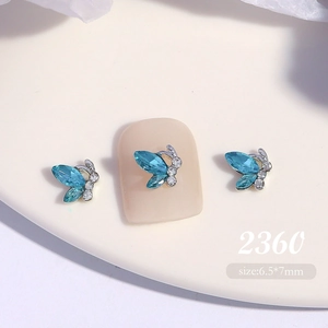 Macro shot of blue crystal butterfly nail charms sized 6.5x7mm on a nude display tip