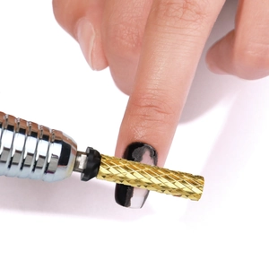 Macro shot of golden cylindrical alloy nail drill bit on handpiece for professional removal