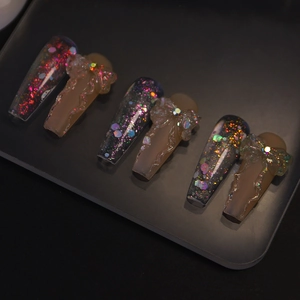 Detail of long coffin nails featuring glitter starscape and pink matte 3D bow design
