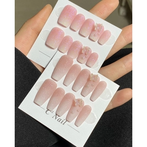 Detail of pink gradient press-on nails with 3D butterfly, pearls and fine glitter