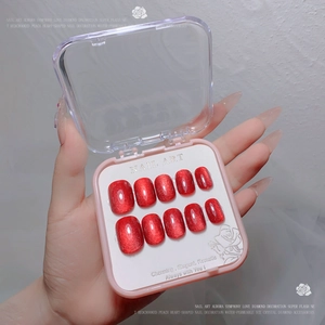 Macro detail of red cat-eye press-on nails with velvet texture in a pink portable box