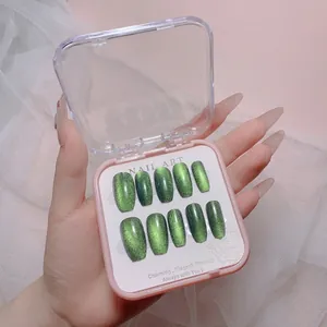 Close-up of green cat eye press-on nails in a long trapezoid shape with shimmering finish