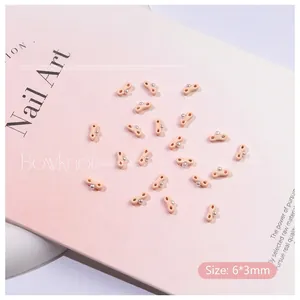 Close-up of 6x3mm apricot ribbon bow nail charms with silver micro beads for nail art