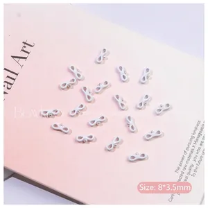 Close-up of 8x3.5mm white bowknot nail charms with center pearl bead for DIY nail art
