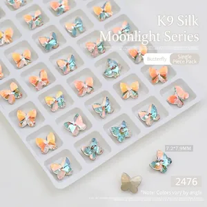Detailed view of K9 butterfly nail crystals with aurora finish in a white organizer tray