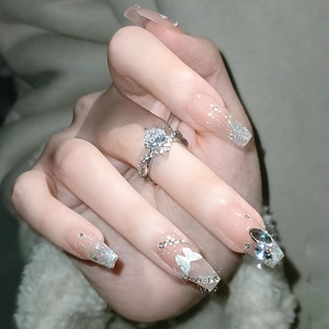 Long square nails with 3D butterflies, rhinestones, and silver zircon ring on a soft background