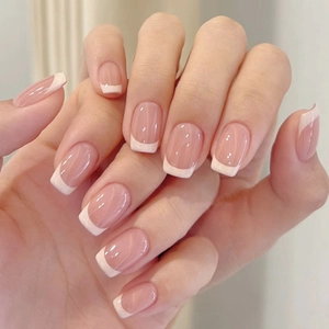 Close-up of nude pink French press-on nails with white tips and high-gloss finish