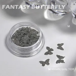 Macro view of metallic grey butterfly nail charms with laser glitter in a clear round box