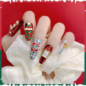 Close-up of Christmas press-on nails with 3D tree, gift box, and red bow details