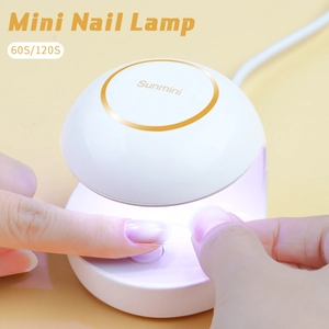 Mini UV LED nail lamp with 60s/120s timer curing a fingernail on a yellow background