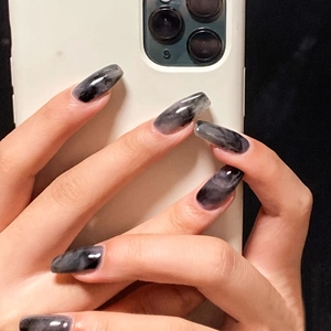 Long trapezoid press-on nails with dark marble ink texture and glossy finish on hand