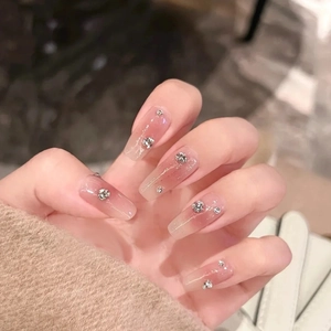 Detailed close-up of long coffin nails with pink gradient and small crystal accents