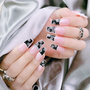 Dettaglio di unghie coffin con punte nere a fiocco di neve e piccoli strass brillanti